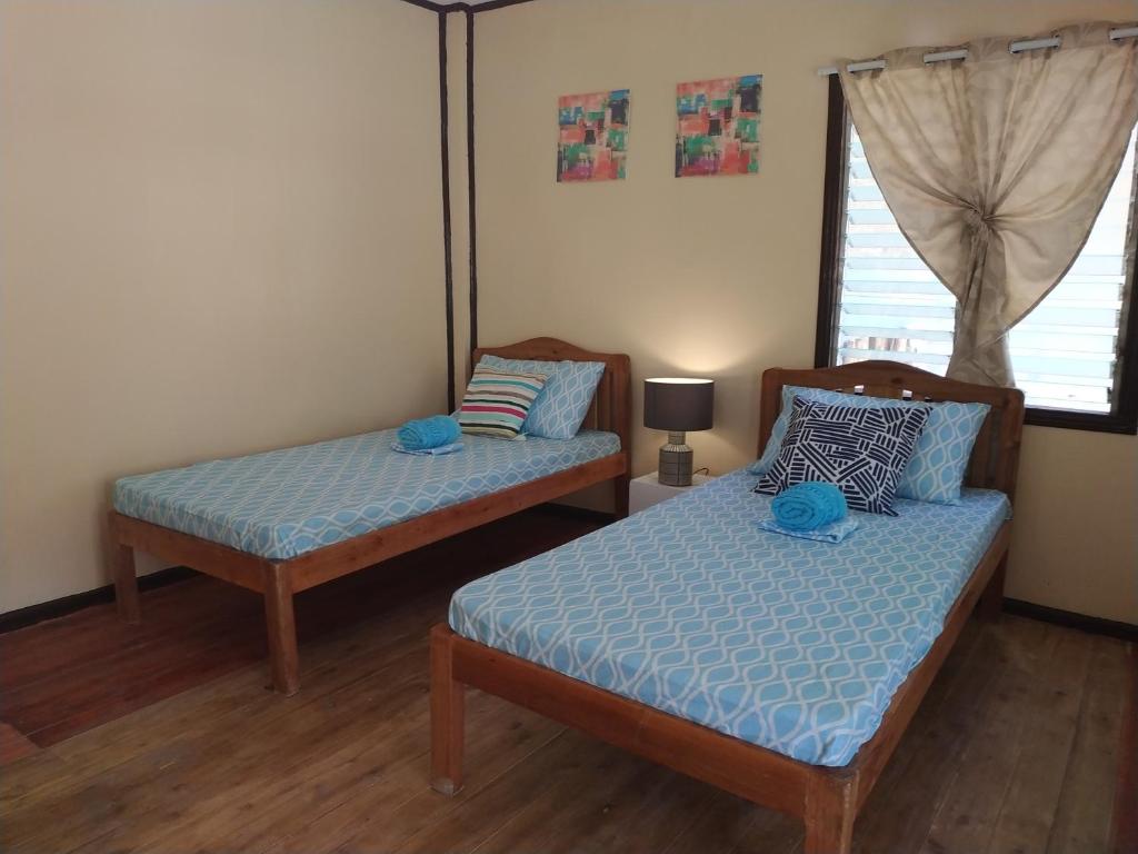 a bedroom with two beds and a window at Nelmann's Nipa Huts in San Vicente
