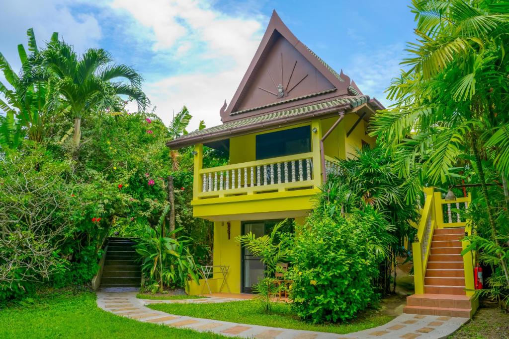 una casa gialla con tetto a gambero di Chez Charly Bungalow a Nai Yang Beach