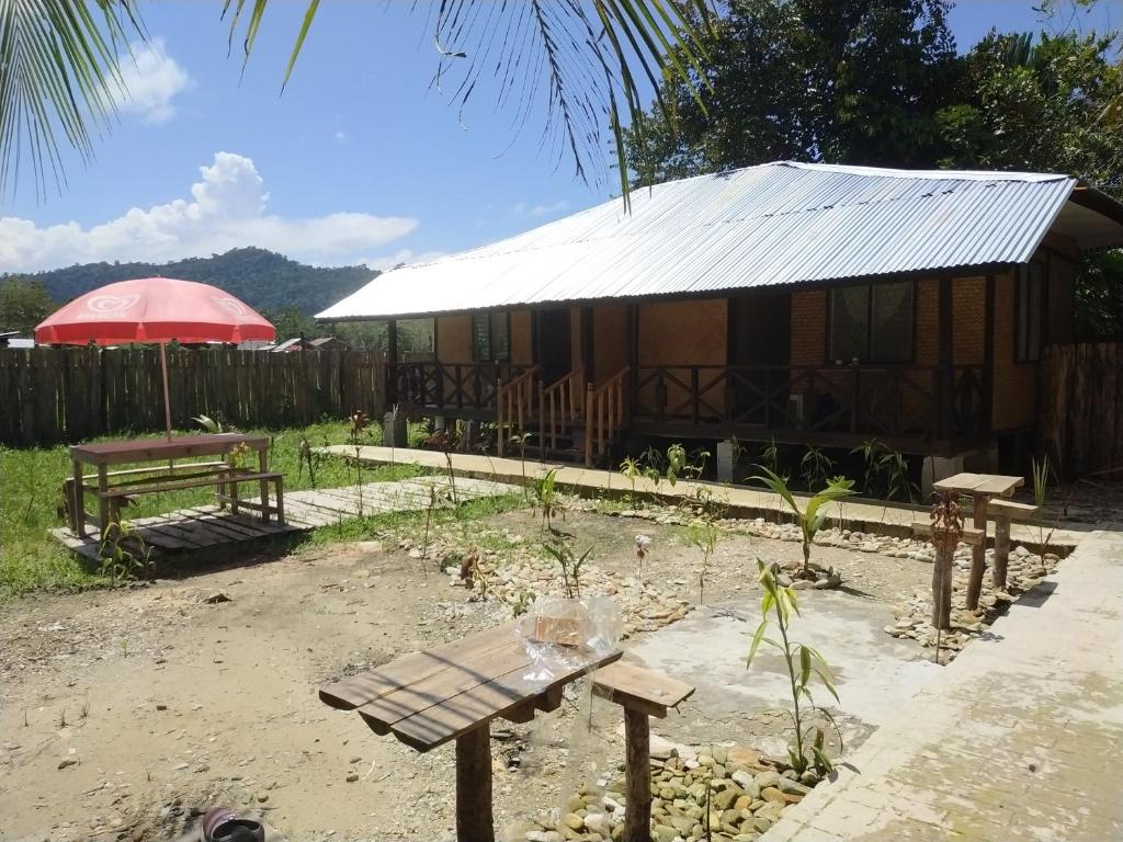 a house with a table and a bench in front of it at Nelmann's Nipa Huts in San Vicente