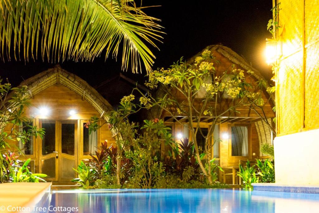 a house with a swimming pool at night at Cotton Tree Cottages in Gili Trawangan