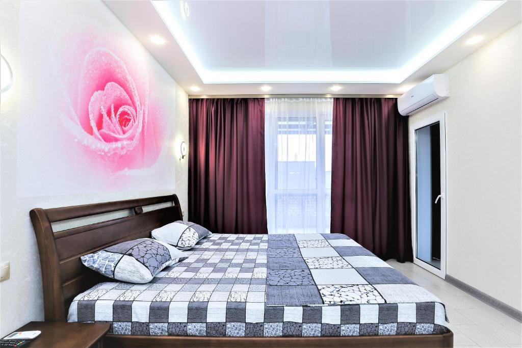 キーウにあるАпартаменты с террасойのベッドルーム1室(ベッド1台付)が備わります。壁にはピンクの花が飾られています。