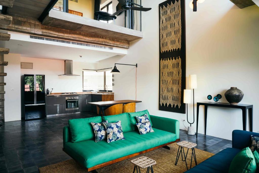 Una sala de estar con un sofá verde y una cocina. en Urban Residences - Siem Reap, en Siem Reap