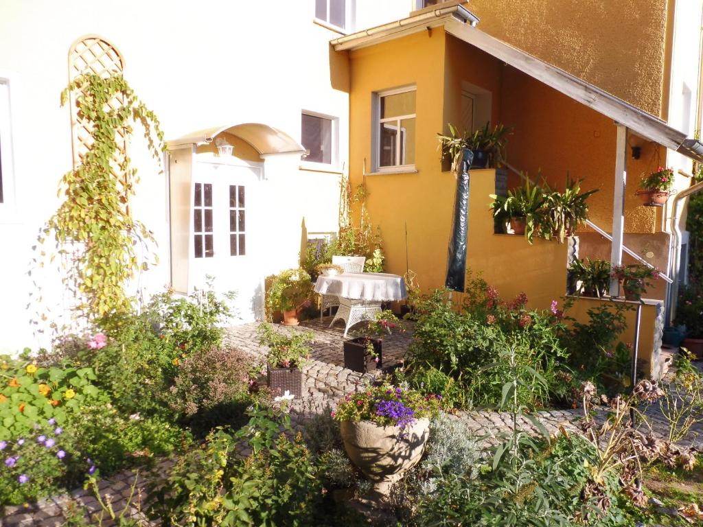 a garden in front of a yellow house with plants at Ferienwohnung Simone in Radebeul