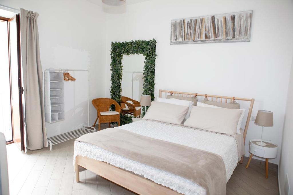 a white bedroom with a white bed and a green ivy arch at Vicolo 8 in Sorrento