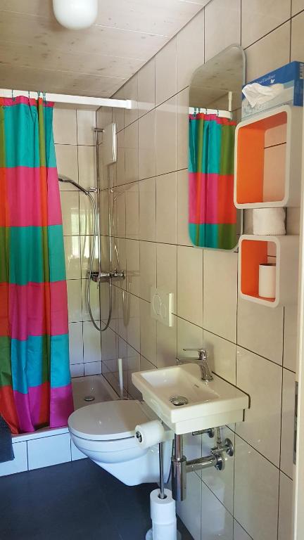 y baño con lavabo y cortina de ducha de arco iris. en b&b krättli, en Eggiwil