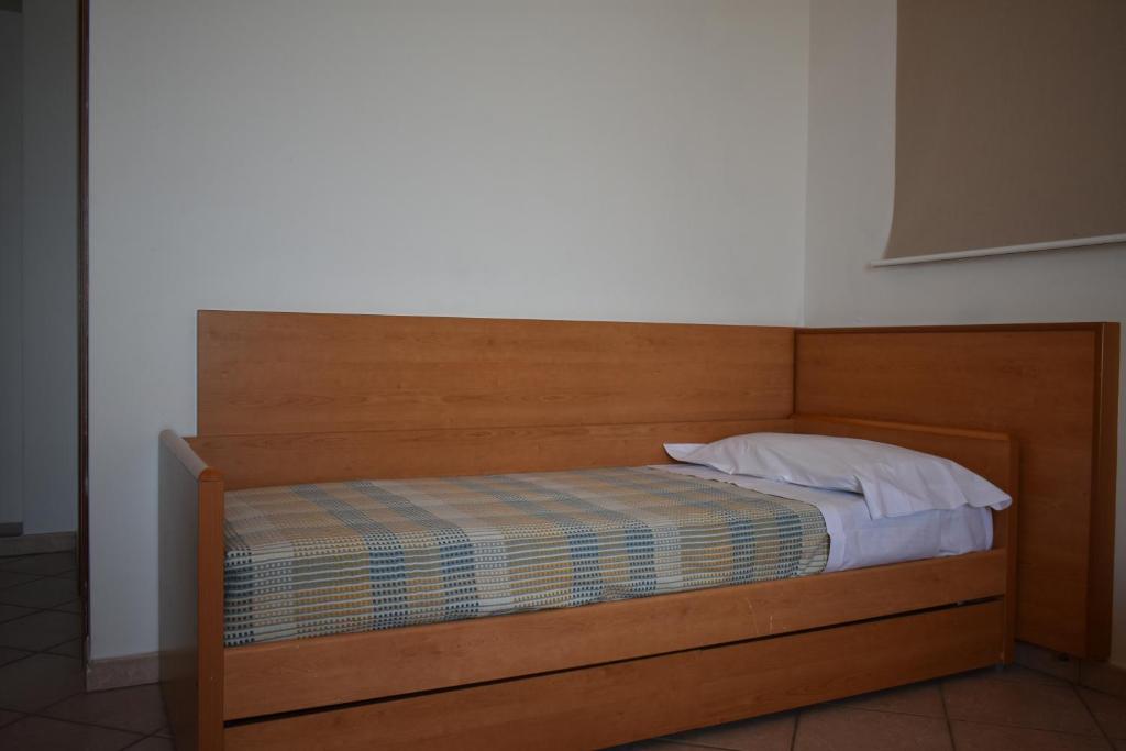 a bed with a wooden headboard and a pillow at Hotel Amyclae in Sperlonga