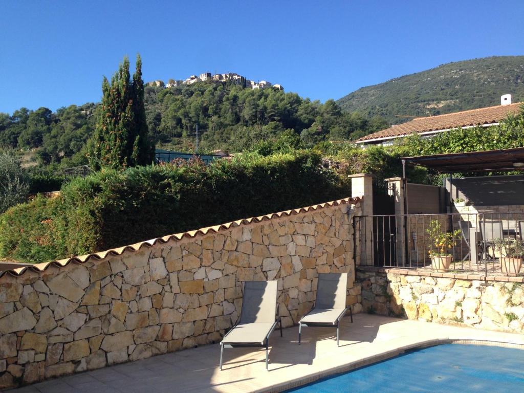 two chairs and a wall next to a swimming pool at appartement en rez de villa in Gattières