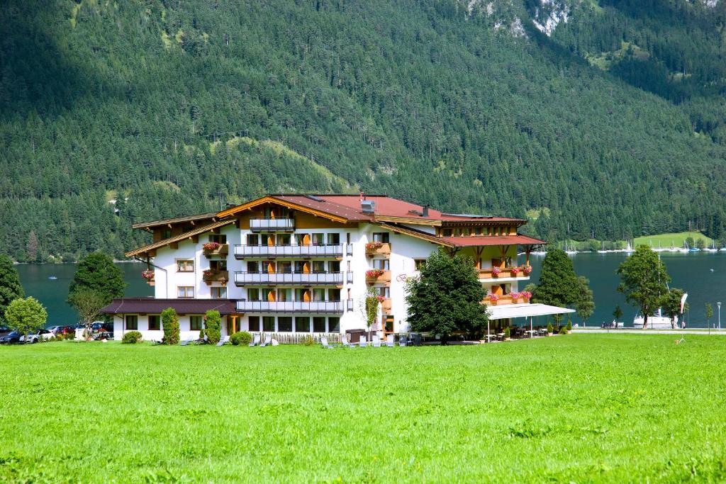a hotel with a green field in front of a mountain at Hotel Bergland in Pertisau