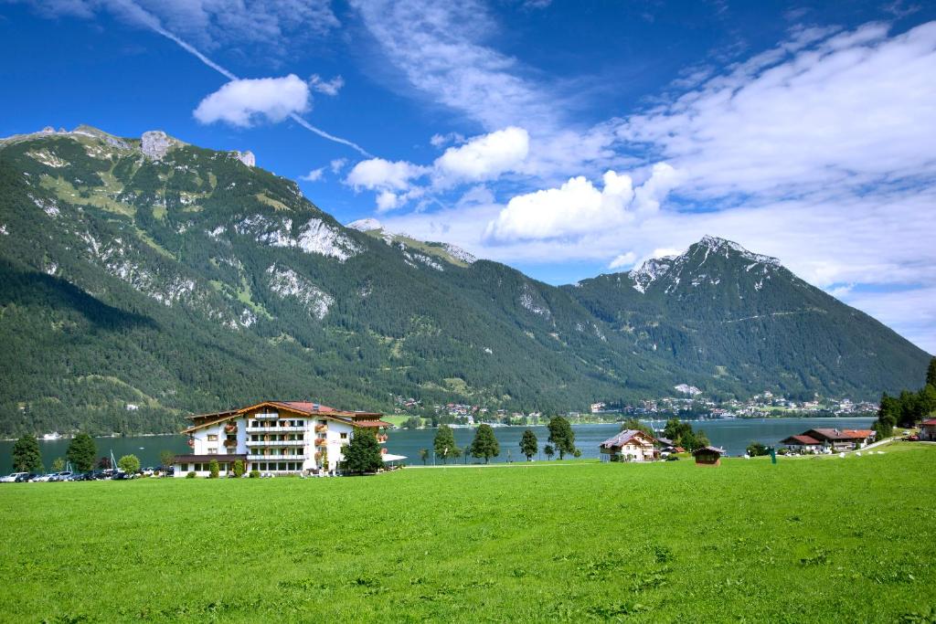 a green field with a building in front of a mountain at Hotel Bergland in Pertisau