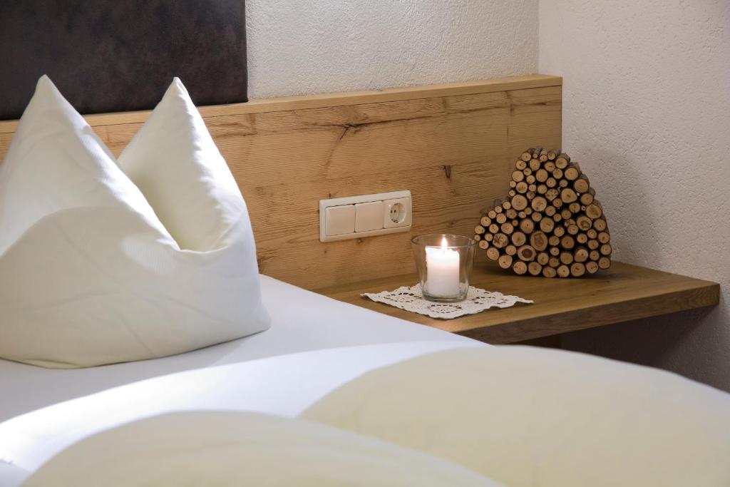 a bed with a pillow and a candle on a shelf at Hotel Bergland in Pertisau