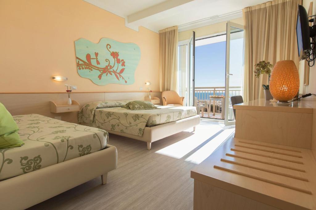 a hotel room with two beds and a balcony at Savoy Hotel in Marina di Pietrasanta