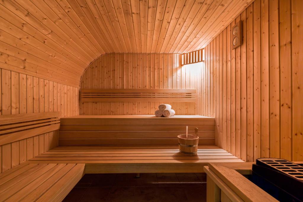 Bright wooden sauna interior with tiered benches, bucket on bench and neatly rolled towels.