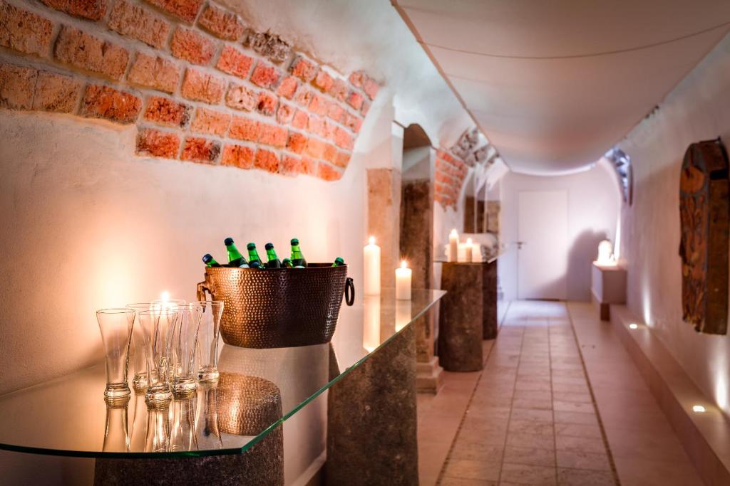 Glass-topped table holding ice bucket of green bottles, empty glasses and lit candles in arched corridor.
