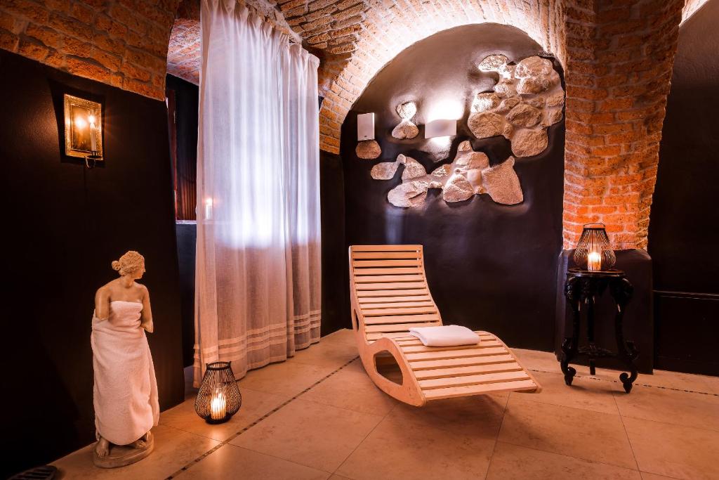 Cozy relaxation room with brick arches, wooden lounge chair, draped statue and soft candlelight.