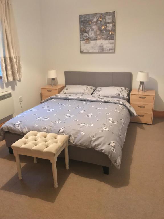 a bedroom with a bed with a blue comforter and a chair at 3 coach house balnagown in Tain
