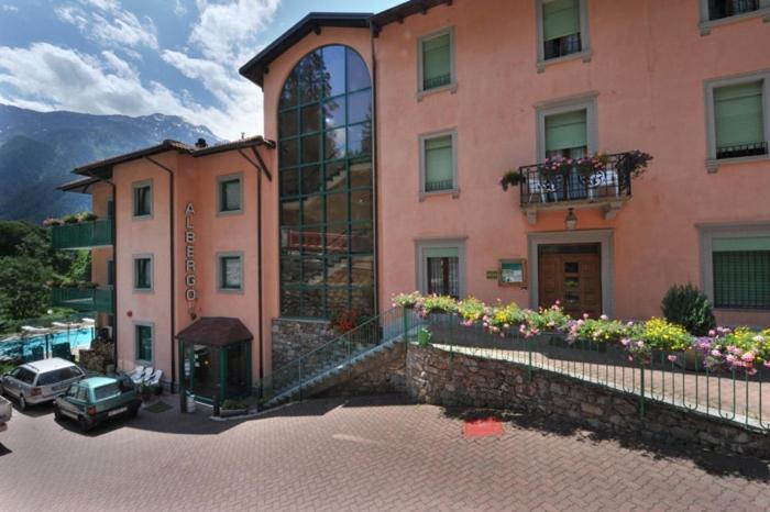 un grand bâtiment rose avec des fleurs devant lui dans l'établissement Hotel Torre, à Sondalo