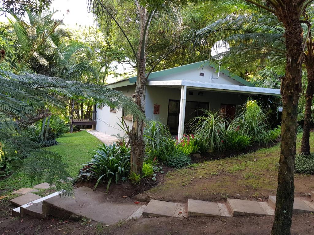 a house with a green roof and trees at African Dwarf Kingfisher Guesthouse in Eshowe