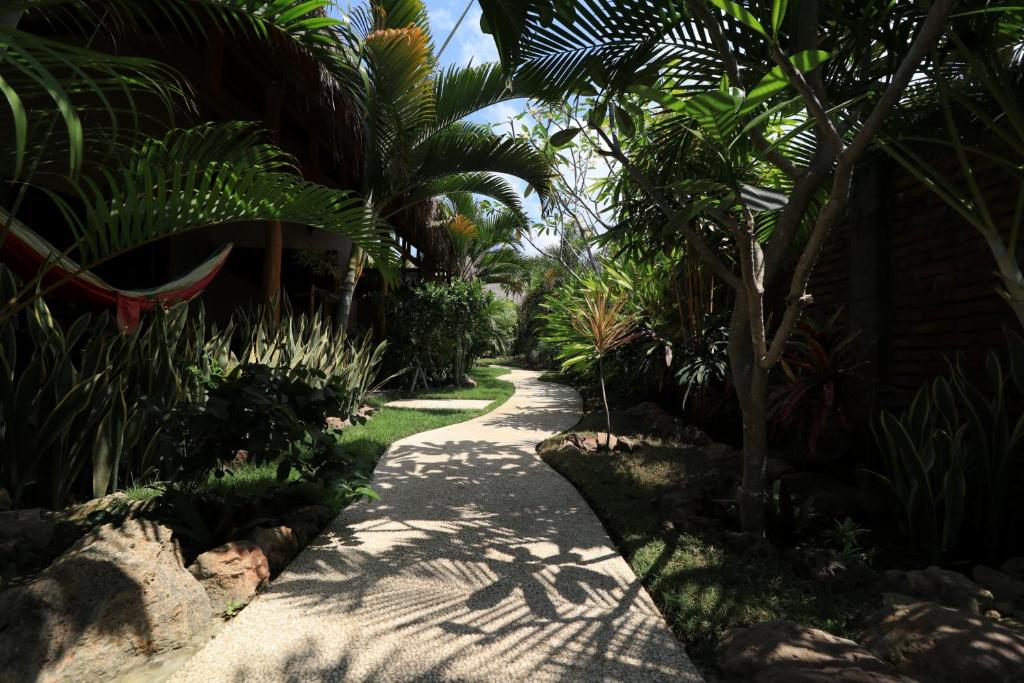 a path through a garden with palm trees at Albany Home Stay in Kuta Lombok