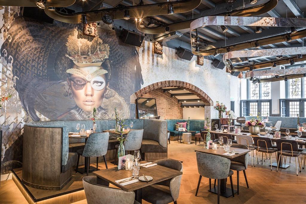 een restaurant met tafels en stoelen en een grote muurschildering bij 't Goude Hooft in Den Haag