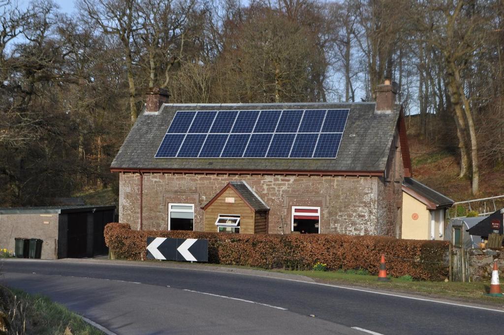 une maison avec des panneaux solaires sur le toit dans l'établissement Bridgehill Cottage Bed & Breakfast, à Crieff