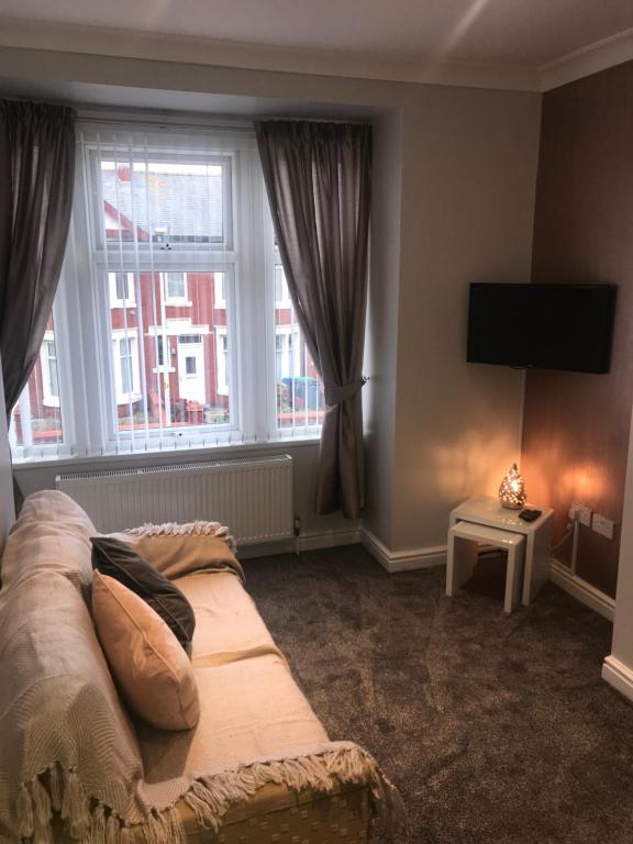 a living room with a couch and two windows at Cornwall Apartments in Blackpool