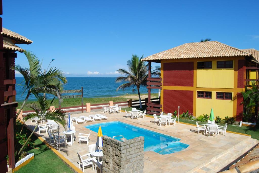 a house with a swimming pool next to the ocean at Pousada Portal da Barra in Marataizes