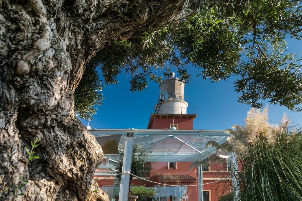 a lighthouse on top of a building with a tree at Faro Capo Spartivento in Chia