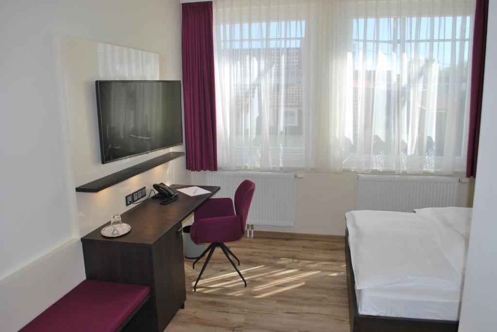 Zimmer mit einem Schreibtisch, einem Bett und einem TV in der Unterkunft Hotel am Berg Esslingen in Esslingen