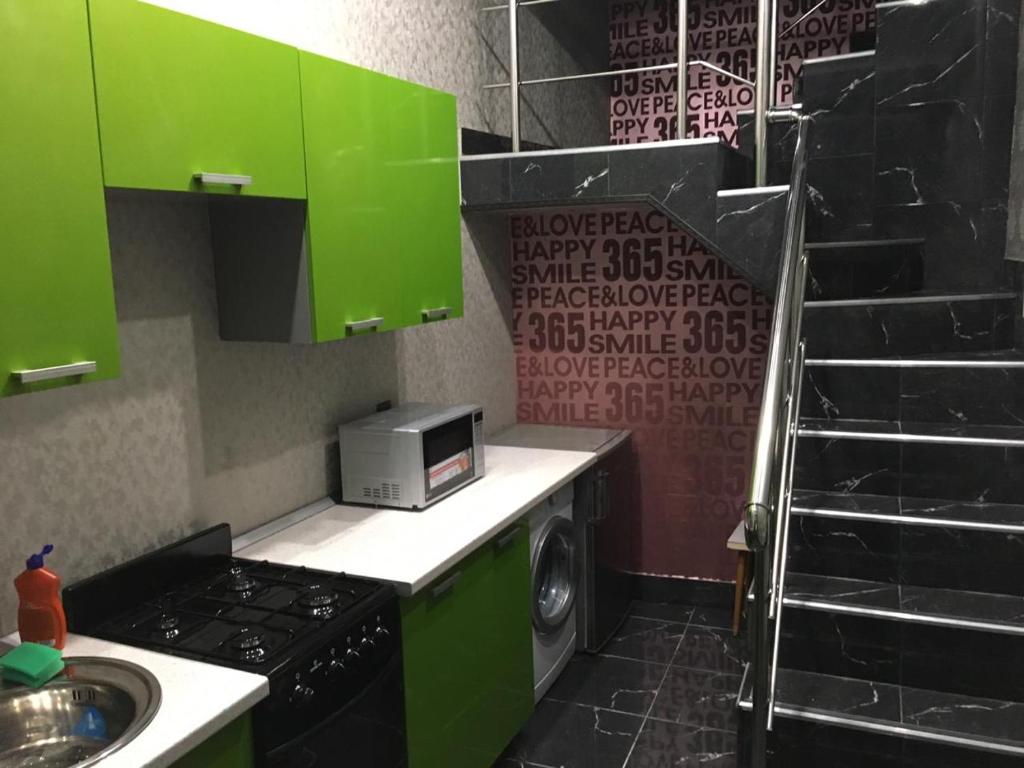 ウラジカフカスにあるОднокомнатная-двухуровневая квартираのキッチン(緑のキャビネット、洗濯機付)