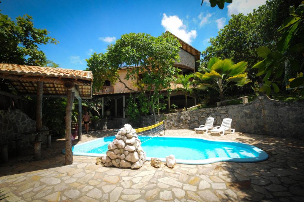 a swimming pool in a yard with two chairs and a house at Casa Atalaia in Pipa