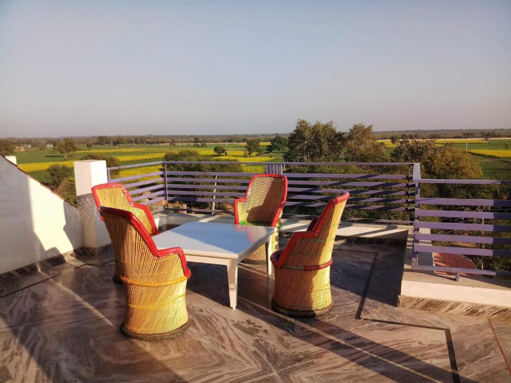 a patio with three chairs and a table on a deck at IbisHouse Farm Stay in Bharatpur