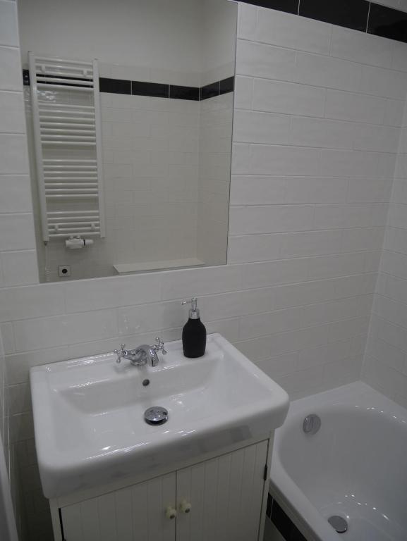 a white bathroom with a sink and a mirror at Moskevská 40 in Karlovy Vary