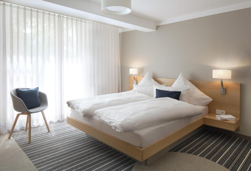 a bedroom with a large white bed and a chair at Hotel Hiller in Abstatt in Abstatt