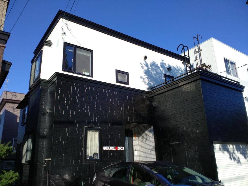 a black and white house with a black brick wall at At Home N23 in Sapporo