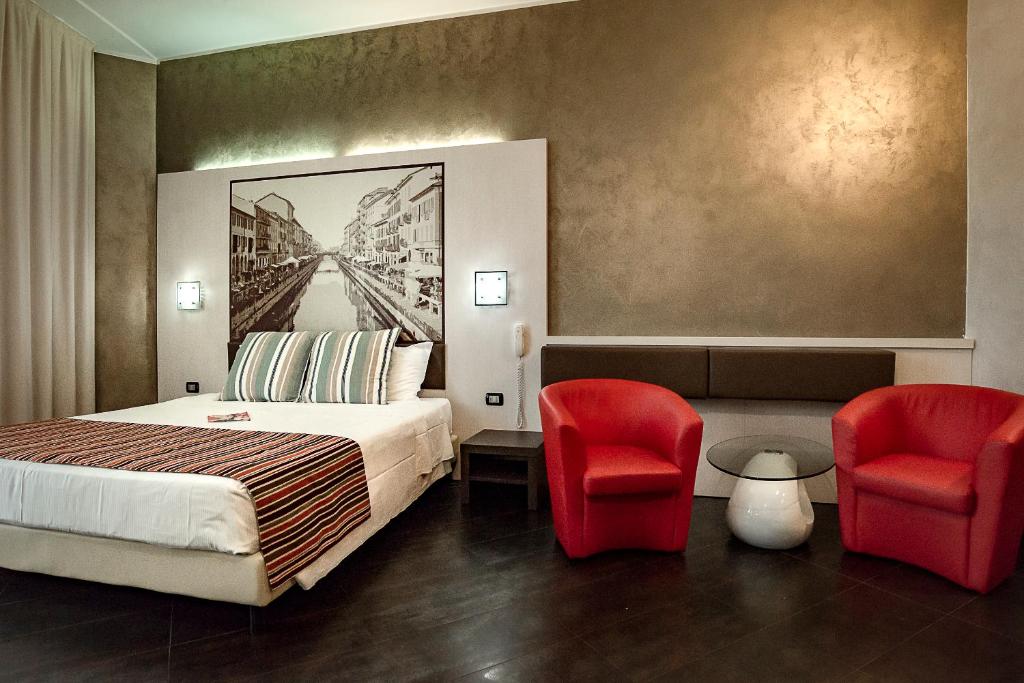 Habitación de hotel con 1 cama y 2 sillas rojas en Hotel Milano Navigli, en Milán