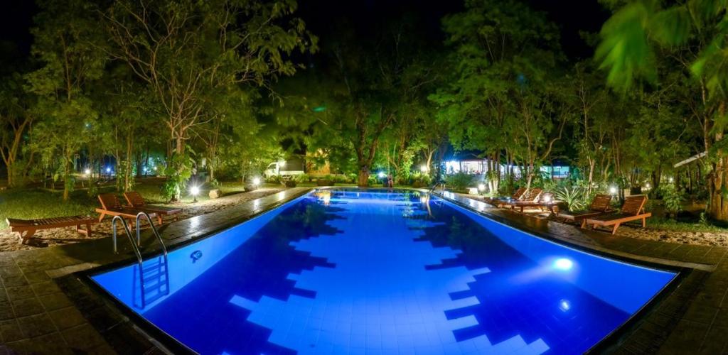 a large swimming pool with blue water at night at Jays Holiday Resort in Habarana