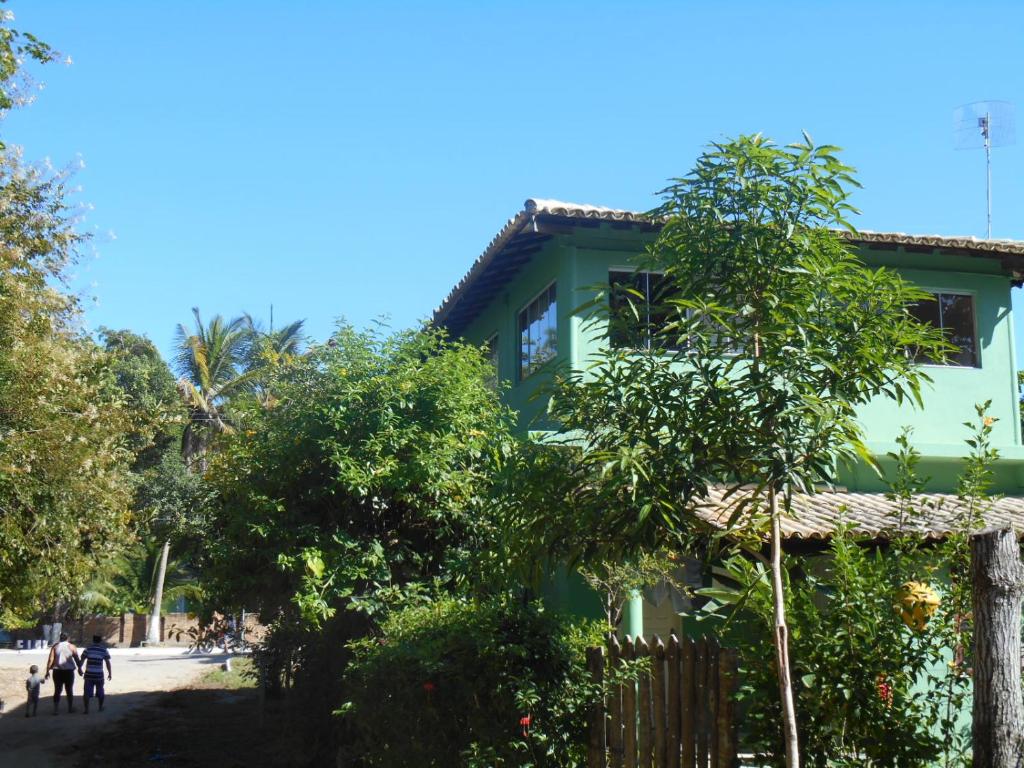 una casa verde con un árbol delante en Apartamento Cumuru en Cumuruxatiba