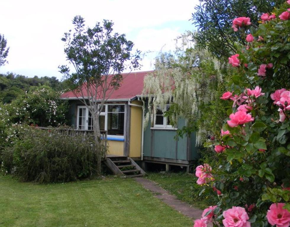 une petite maison avec des roses roses devant elle dans l'établissement The Sandcastle, à Pohara