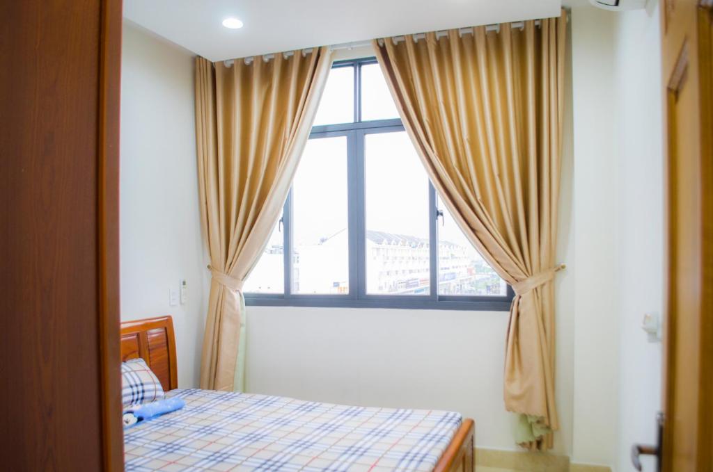 - une chambre avec un lit et une grande fenêtre dans l'établissement The MONDAY APARTMENT, à Hô-Chi-Minh-Ville