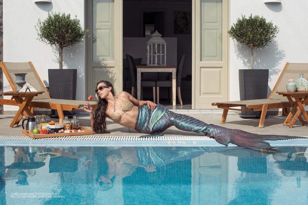a woman is laying on the edge of a swimming pool at Mathios Luxury Homes in Akrotiri