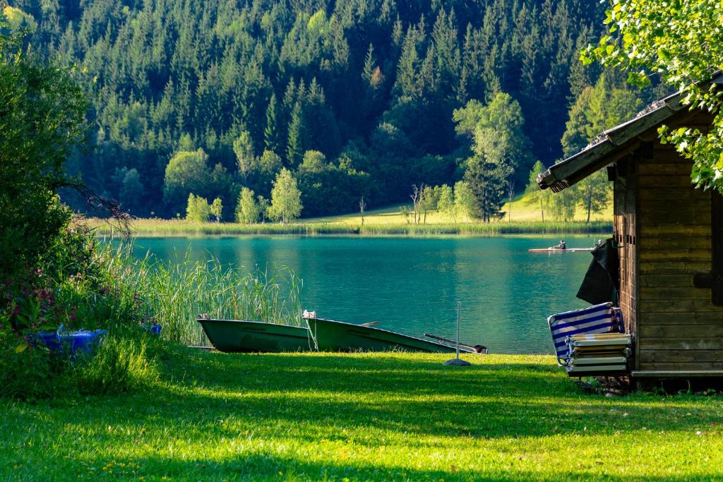 a house and a boat on the shore of a lake at Pension Untergasser in Weissensee