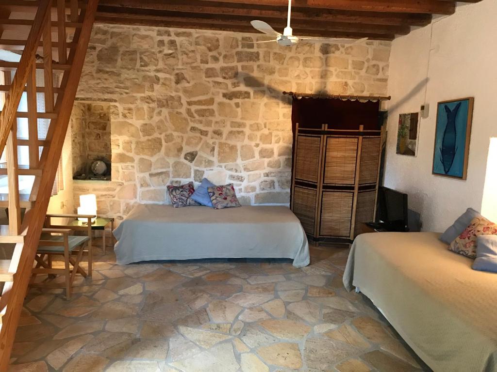 a bedroom with two beds and a stone wall at The "M" House in Gaios
