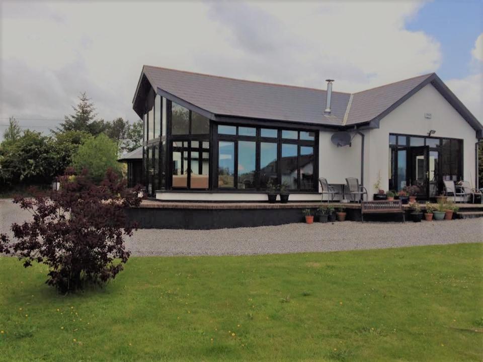 a house with large glass windows on a lawn at ocean view in Wexford