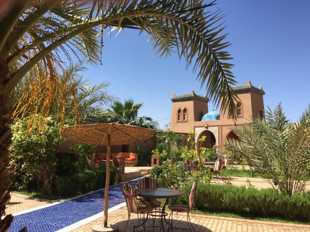 uma mesa com cadeiras e um guarda-sol em frente a uma casa em Le Sauvage Noble em Zagora