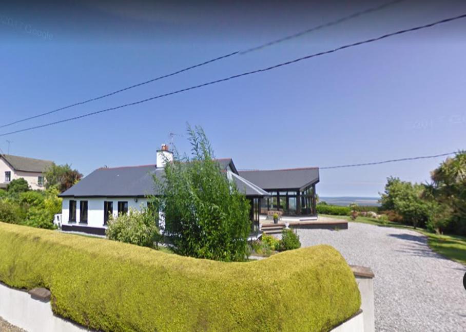 a house with a green hedge in front of it at ocean view in Wexford