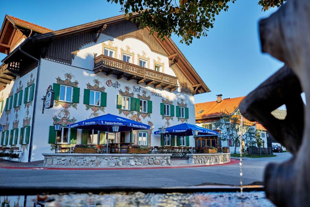 een gebouw met blauwe parasols ervoor bij Ferienwohnungen im Gasthof Stern inklusive KönigsCard in Unterammergau
