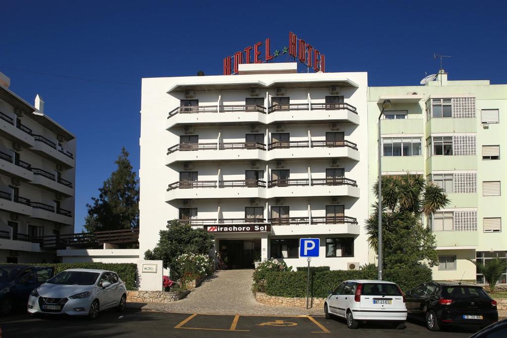 ein großes weißes Gebäude, vor dem Autos parkten in der Unterkunft Portimão Center Hotel by Umbral in Portimão