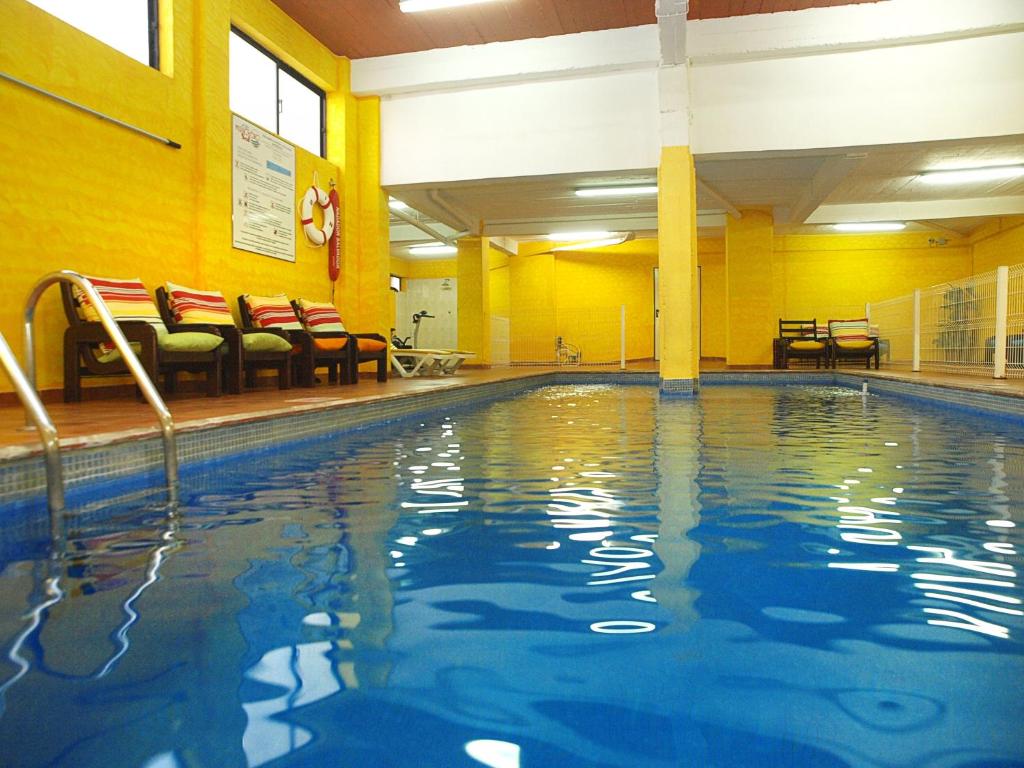 a swimming pool in a hotel room with chairs at Portimão Center Hotel in Portimão