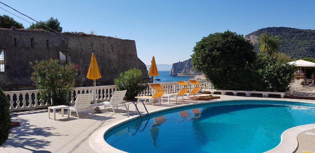 uma piscina com cadeiras e guarda-sóis e o oceano em Park Hotel Castello em Finale Ligure