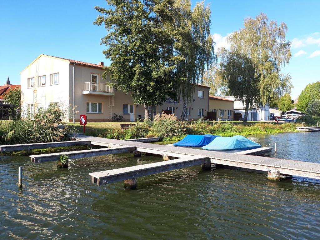 a dock with tents on the water next to a building at Boootshaus - Am Spreeufer in Beeskow